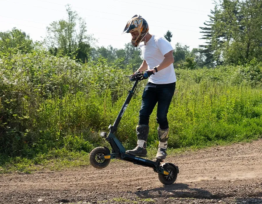 Un pilote casqué sur l'Urbanglide GT Pro, sur un chemin de terre bordé de haies